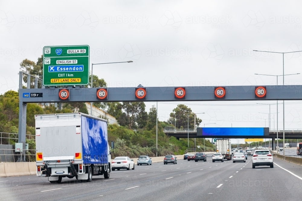 80 speed limit sign above road with traffic on daily commute through city - Australian Stock Image