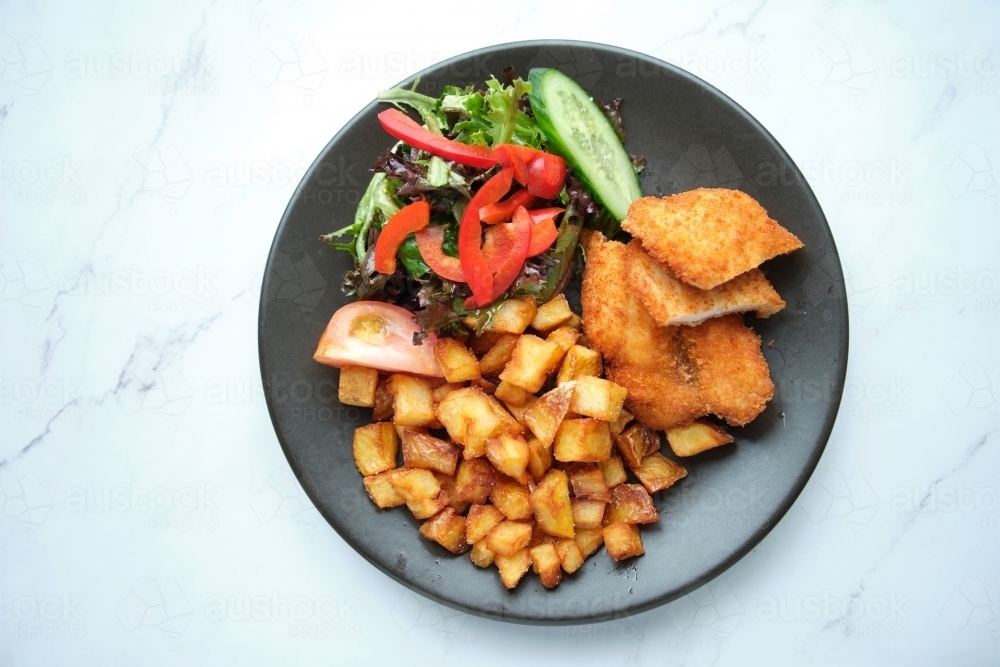 A bowl of diced potatoes, salad and fried meat - Australian Stock Image