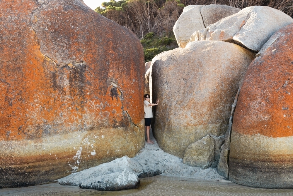 a boy child wearing sun glasses next to boulder rocks at Squeaky beach in Wilson's Promontory South - Australian Stock Image