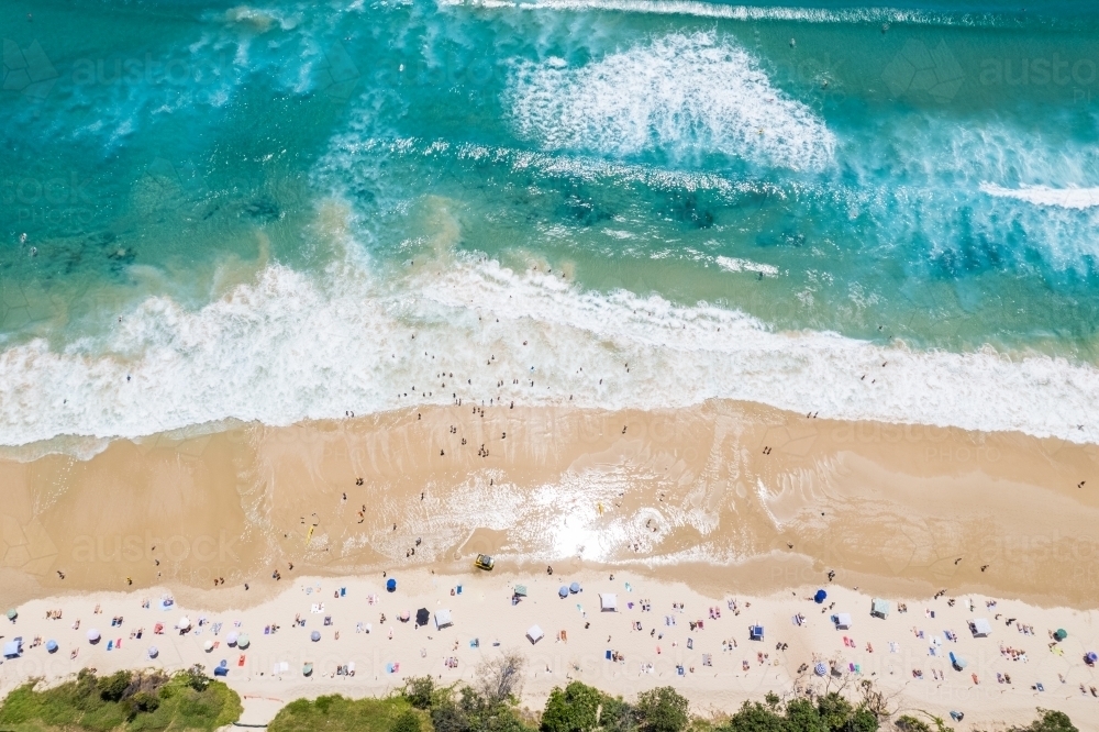 A busy beach day looking down at beach goers as the surf comes in - Australian Stock Image