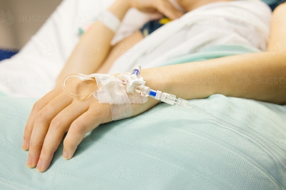 A cannula in the left wrist of a female patient lying on a bed - Australian Stock Image