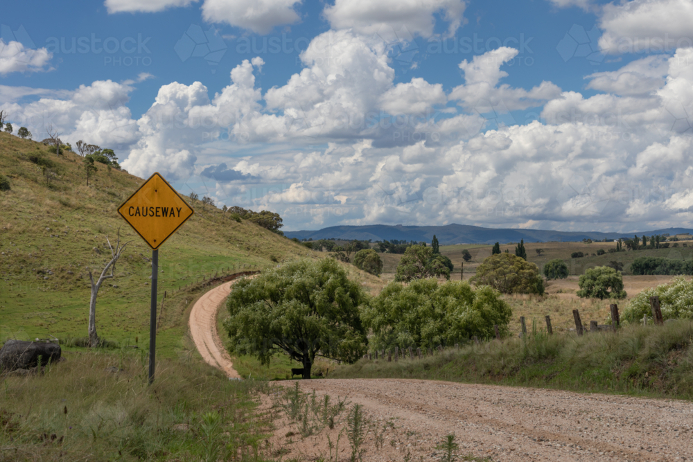 A cloudy sky, a causeway sign and a country road - Australian Stock Image