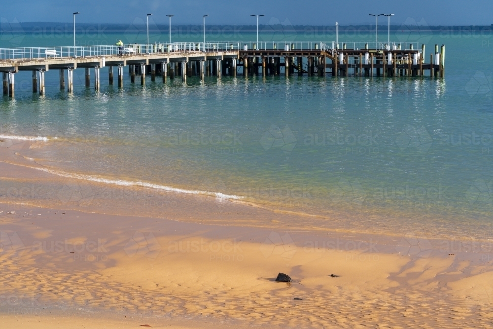 A coastal jetty and its reflection over a calm blue sea - Australian Stock Image