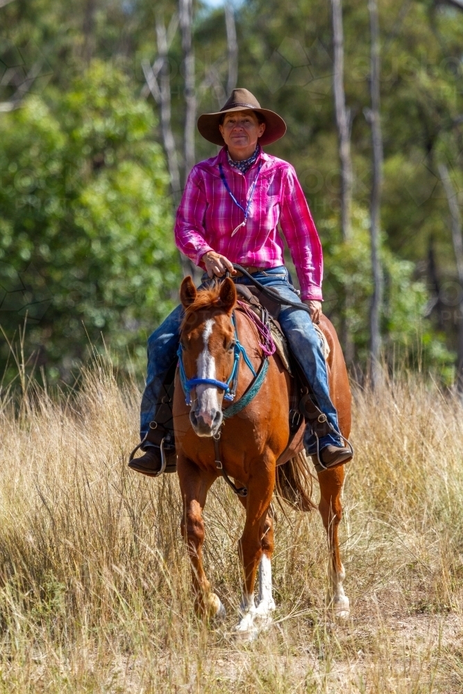 A country lady in her sixties horse riding in the country. - Australian Stock Image