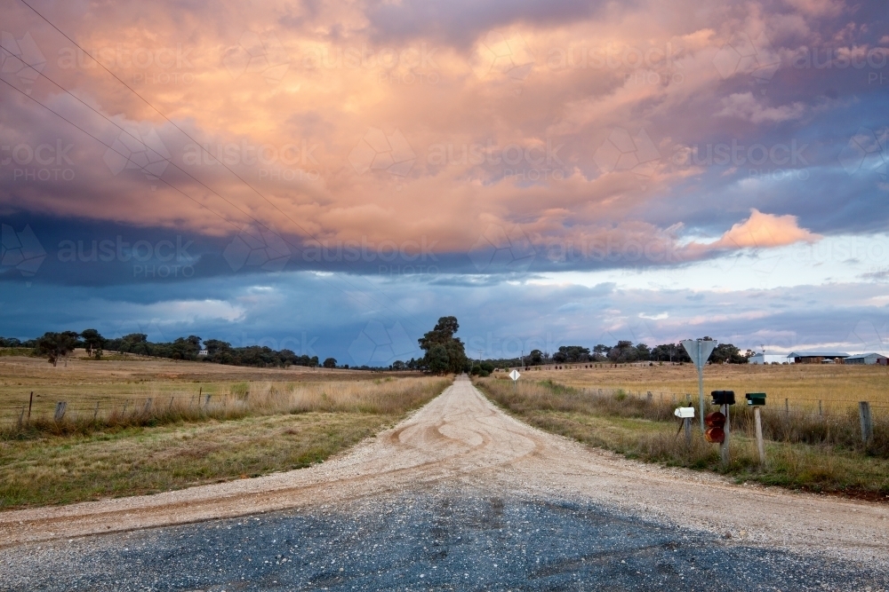 A country road leads off into the distance an under storm clouds - Australian Stock Image