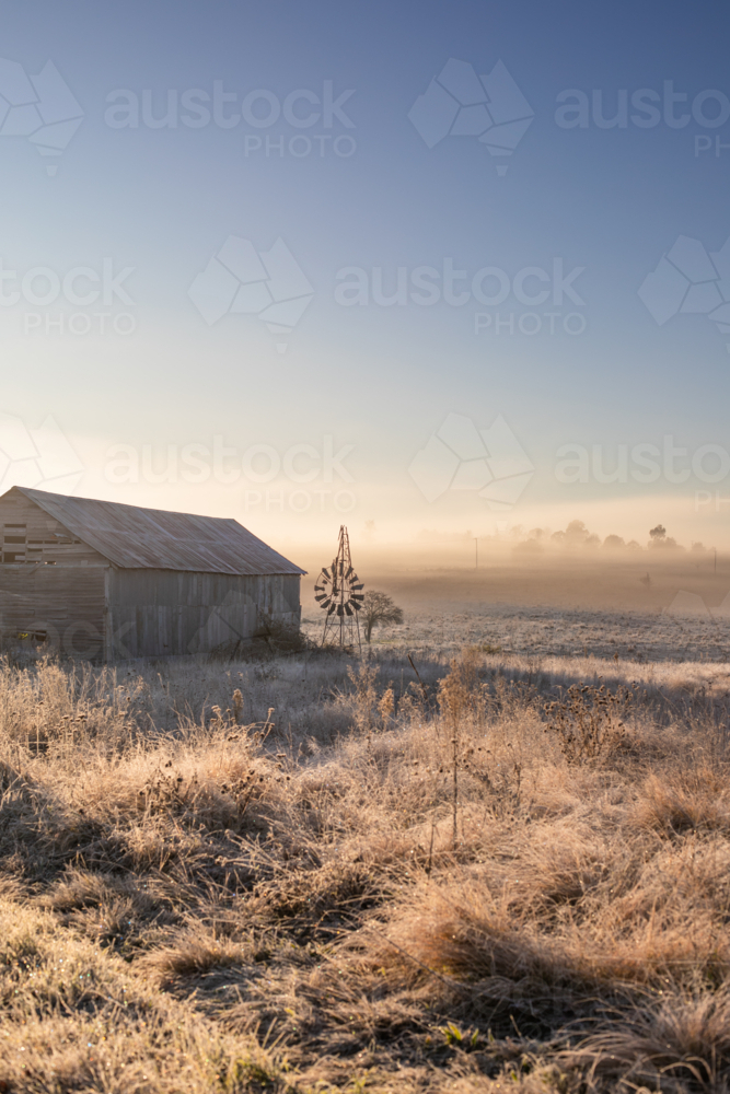 A country scene on a misty morning with a broken windmill and an old country barn - Australian Stock Image