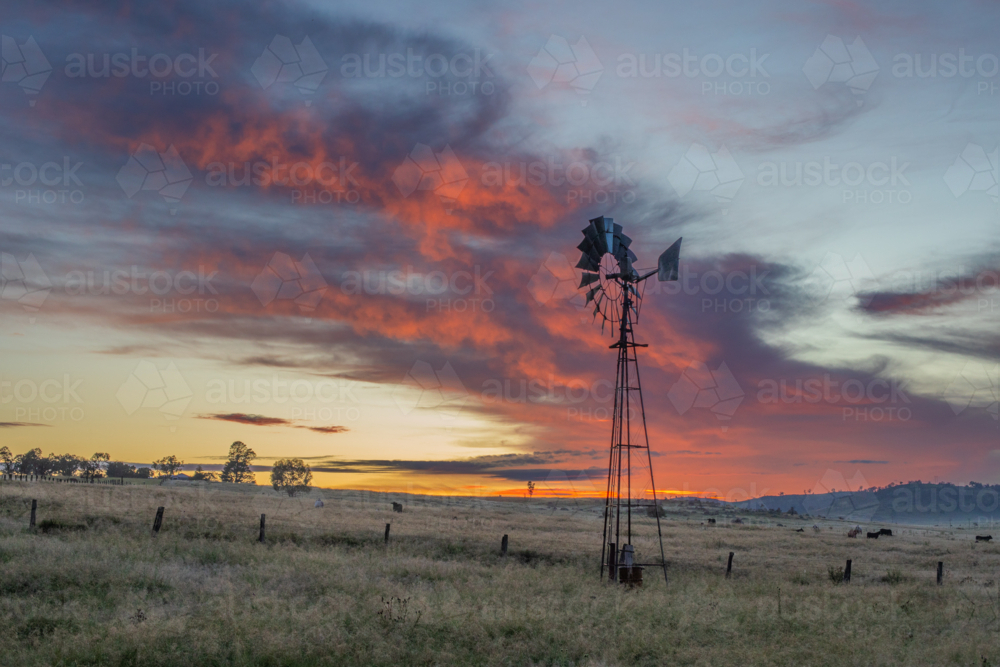 A country windmill in a field under a sunrise sky - Australian Stock Image