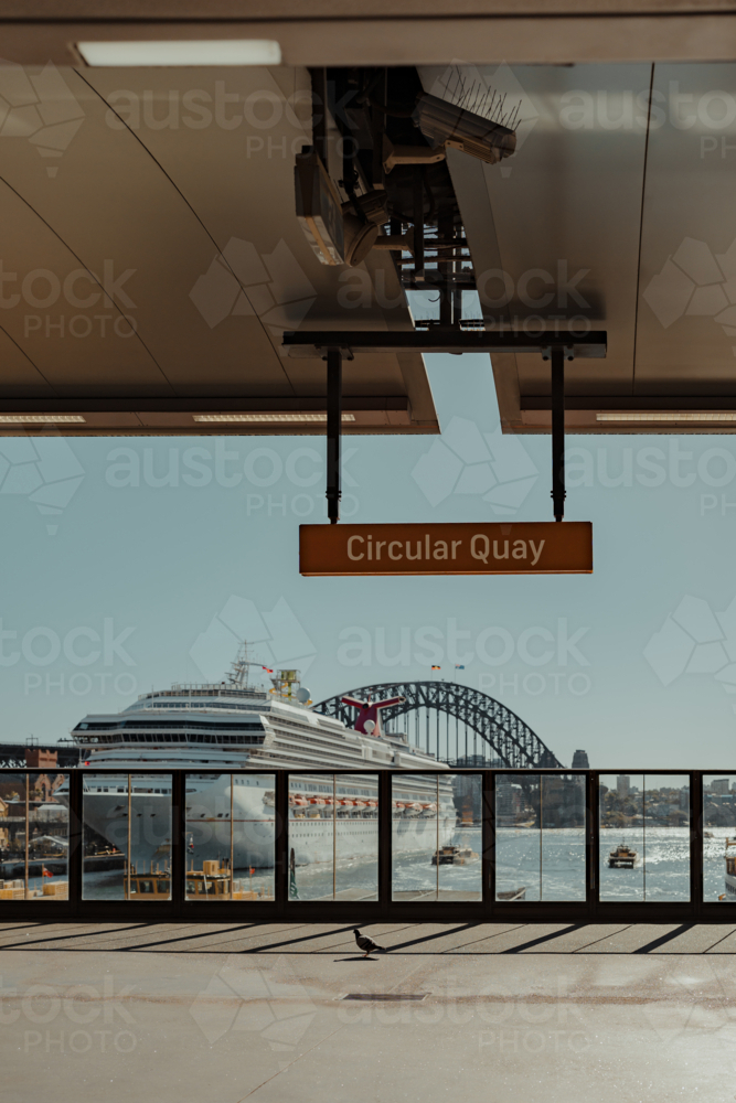 A cruise ship sits in front of the Harbour Bridge as seen from Circular Quay Train Station - Australian Stock Image