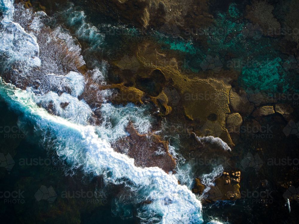 A dark ocean breaks over an exposed reef - Australian Stock Image