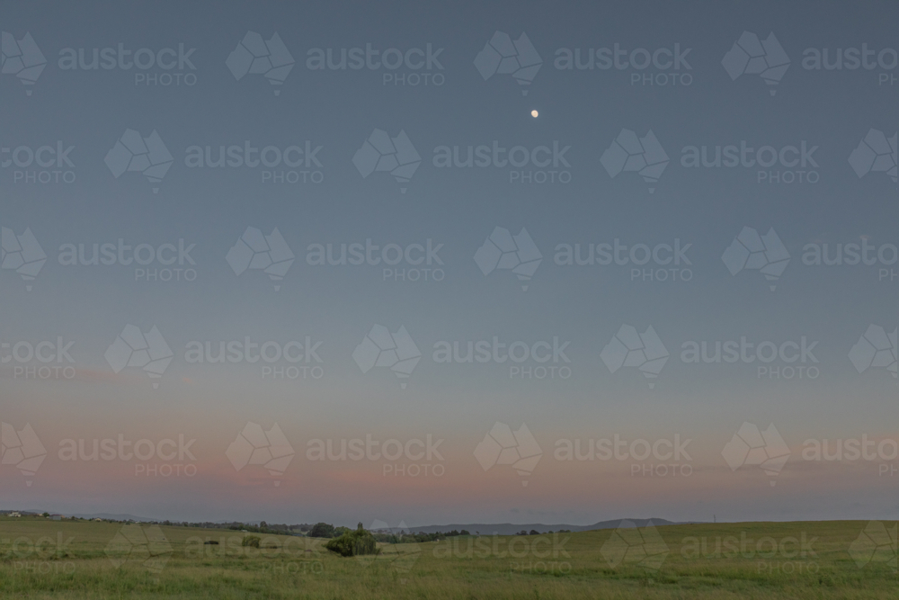 A dawn sky in the country under a setting full moon - Australian Stock Image