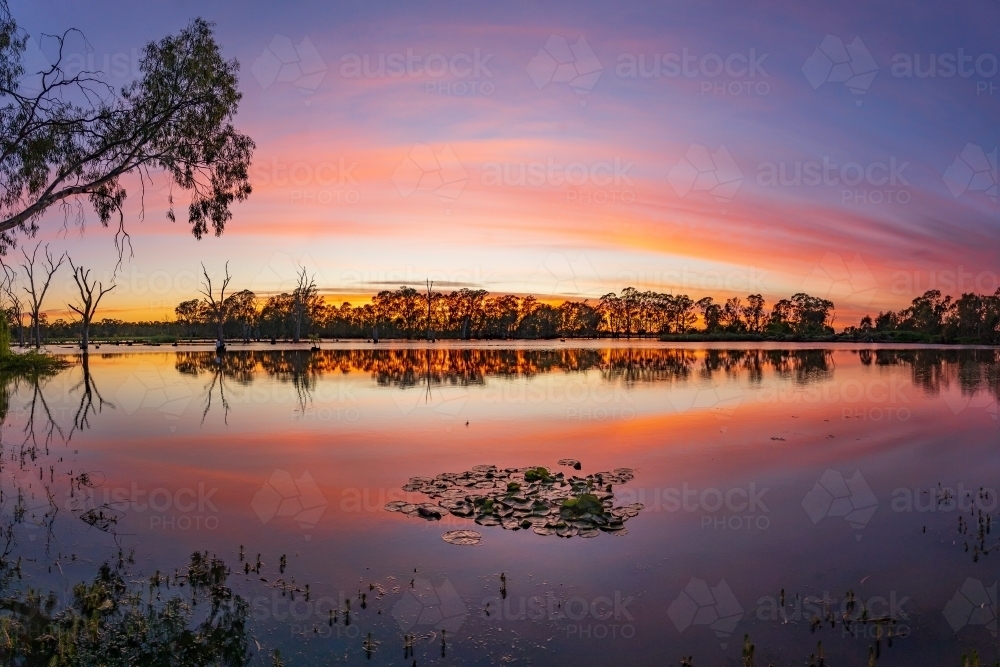 A dramatic dawn sky reflected in the waters of a still river - Australian Stock Image