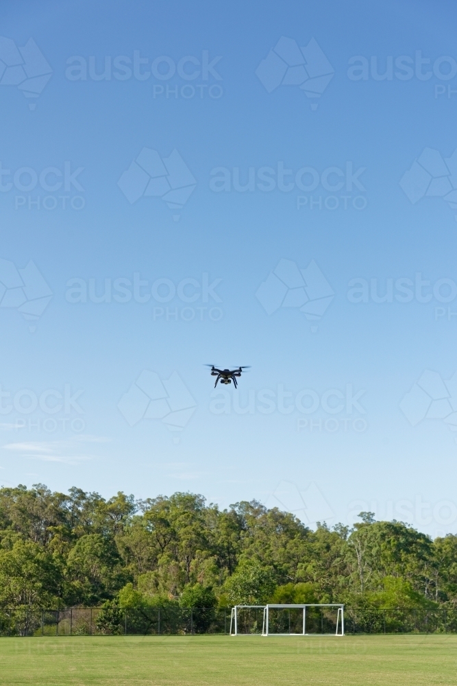 A drone, or UAV, or RPAS hovering over a football field - unmanned aerial vehicle - Australian Stock Image