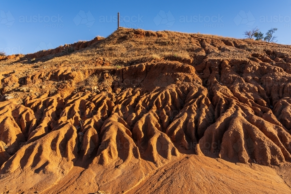 A dry river bed with high eroded sides of red dirt - Australian Stock Image