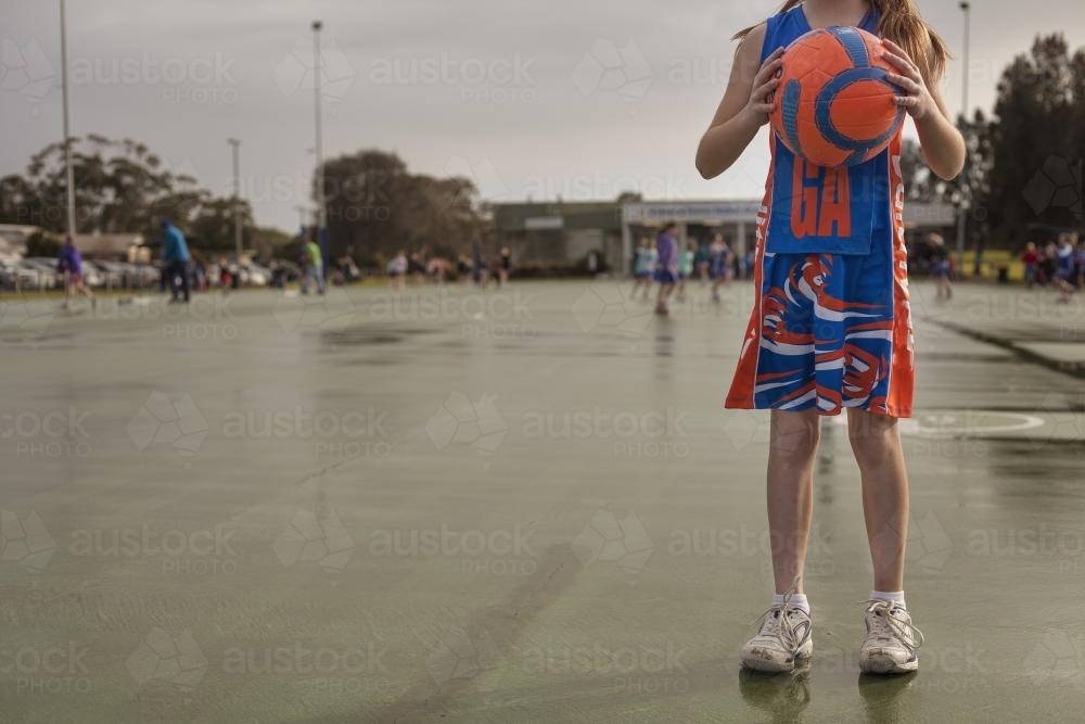 A girl facing camera holding the ball for playing netball - Australian Stock Image