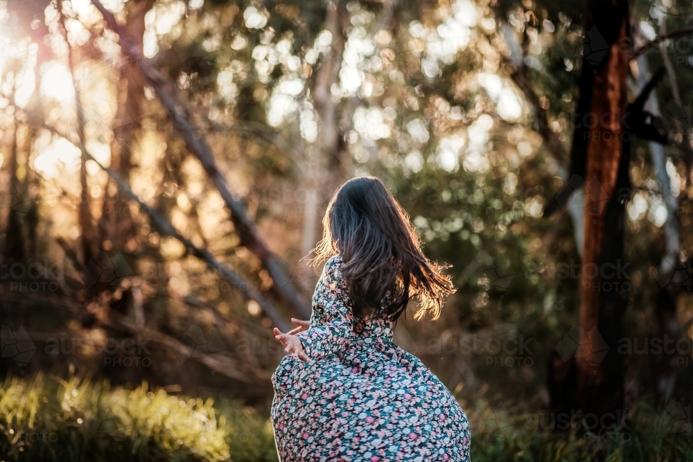 a girl twirling at the park in sunset - Australian Stock Image