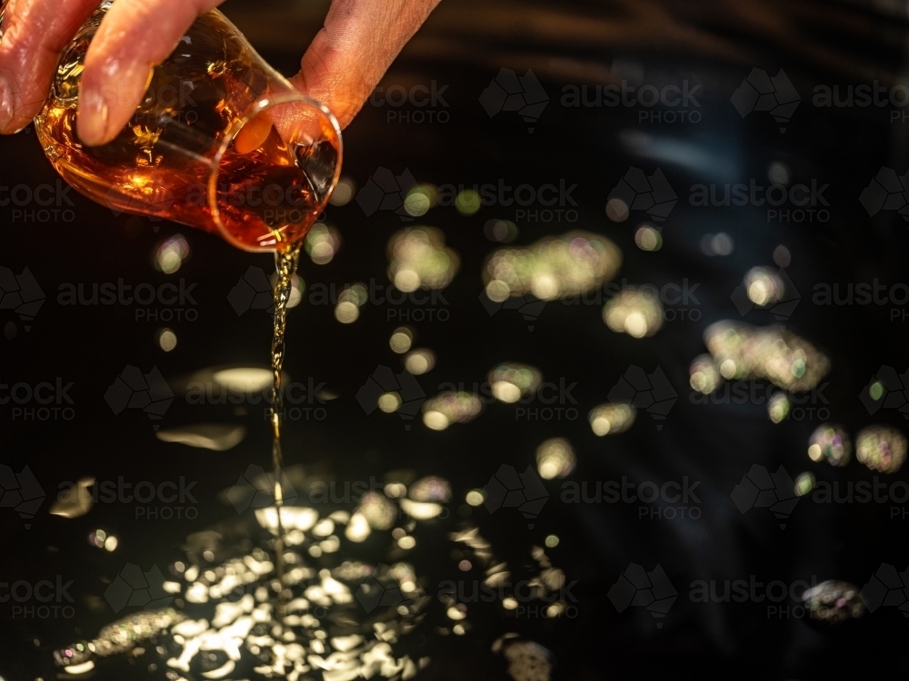 A glass of whisky poured into a whisky still - Australian Stock Image