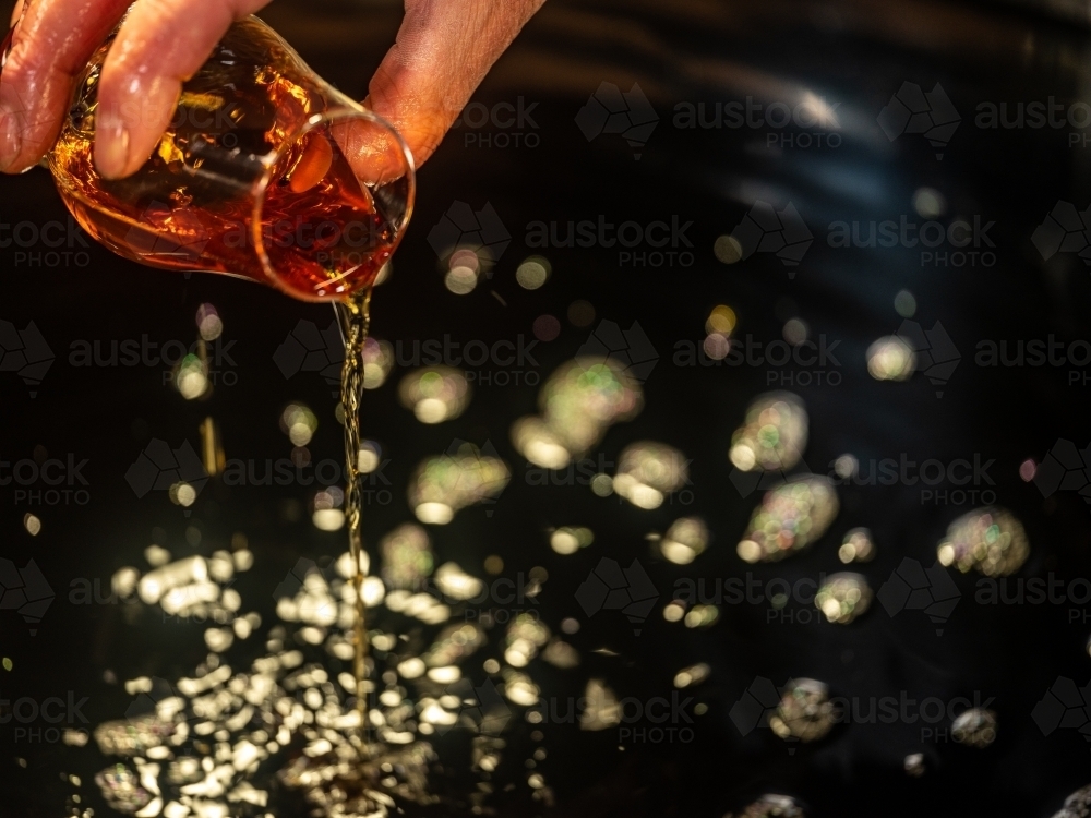 A glass of whisky poured into a whisky still - Australian Stock Image