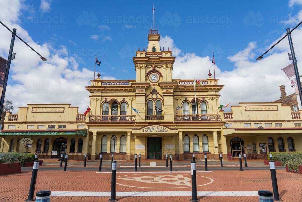 A grand historic Town Hall with a clock tower behind rows of bollards around road partition - Australian Stock Image