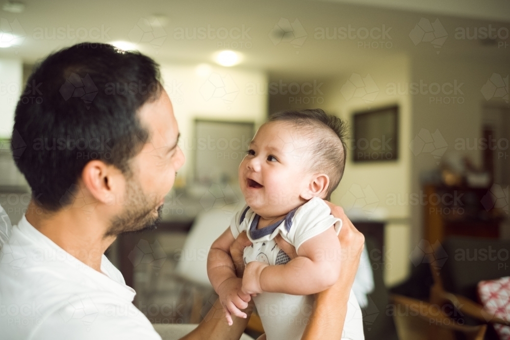 A happy baby smiling at his father - Australian Stock Image