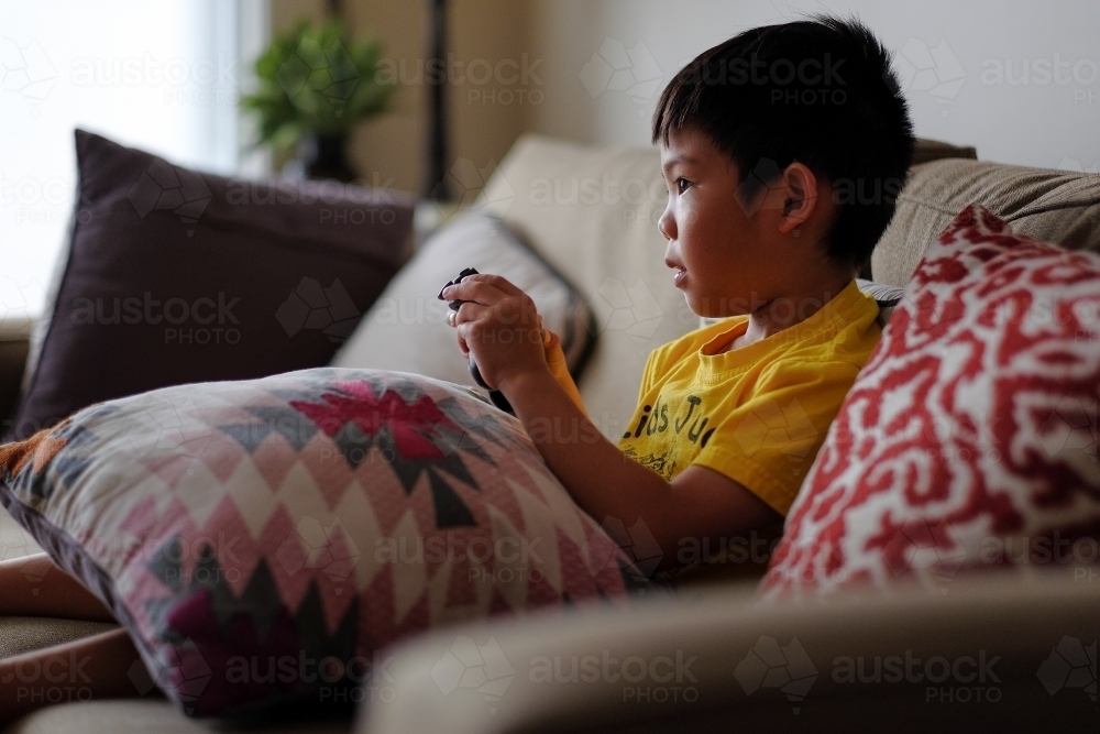 a kid, playing a console game in the living room - Australian Stock Image