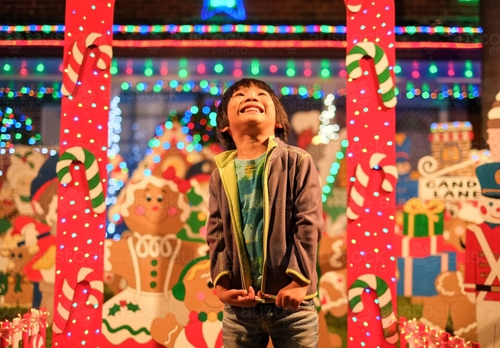 a kid, smiling and dazzled by the Christmas lights and decorations - Australian Stock Image