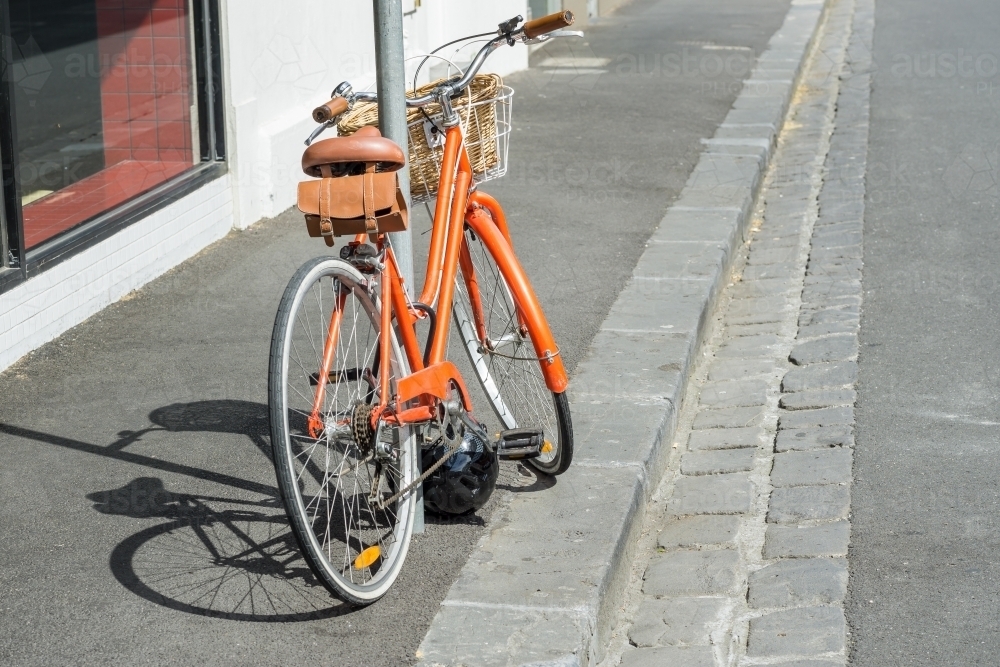 A ladies bicycle leaning against a pole on the footpath - Australian Stock Image