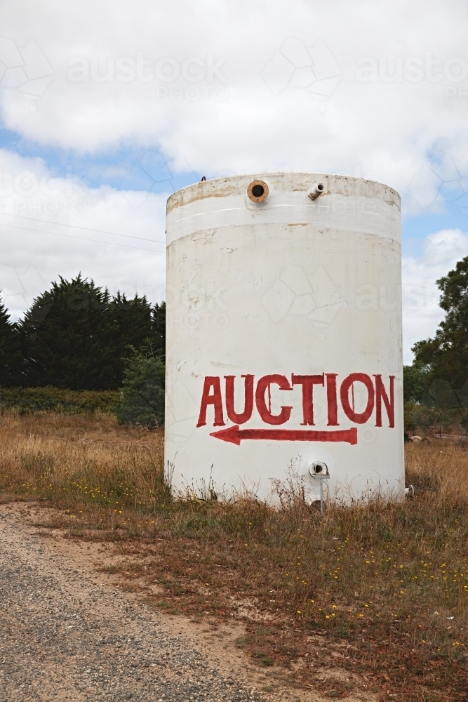 A large cylindrical tank with an "Auction" sign direction - Australian Stock Image