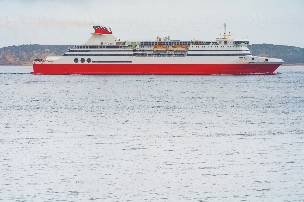 Image of A large red cruise ship on a calm bay with copy space ...