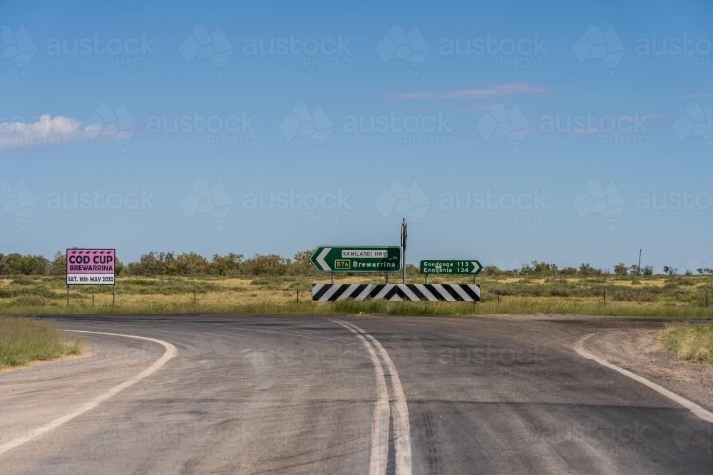 A line down the centre of an outback road leading to a traffic sign - Australian Stock Image