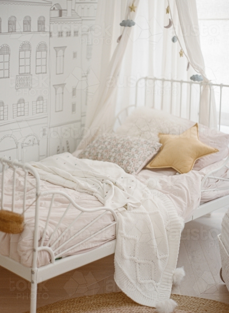 A little girl's bed with a canopy, star and flowers and parisian wallpaper - Australian Stock Image