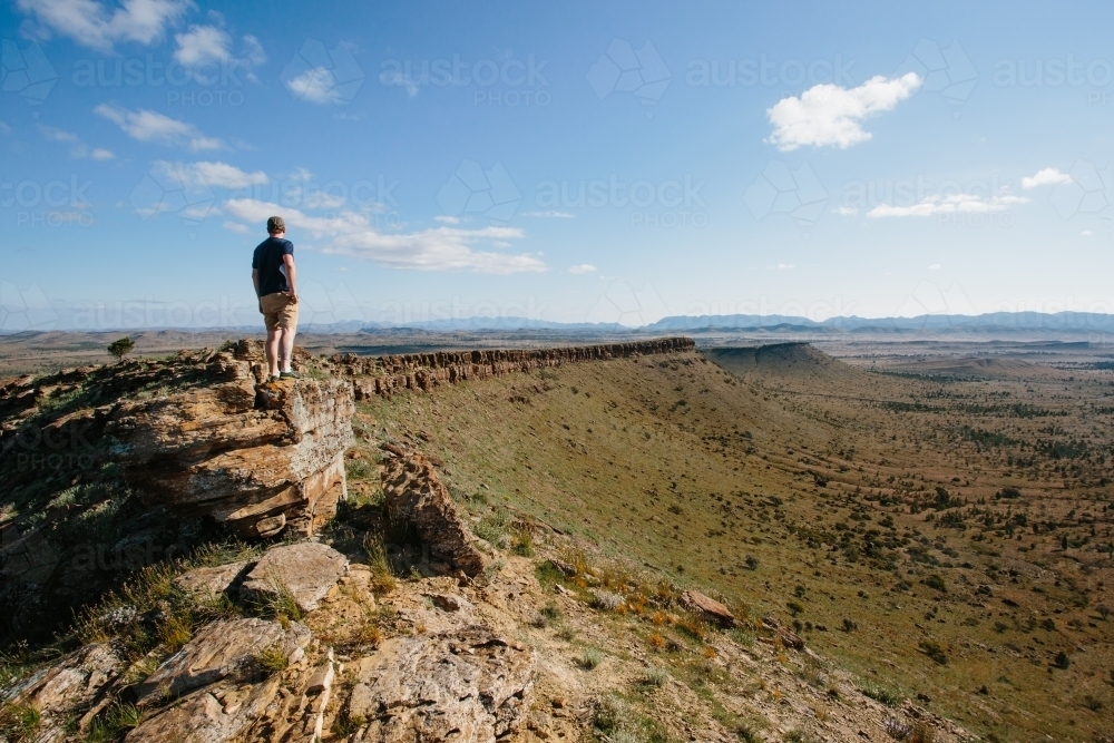 A man in hiking gear overlooking the rugged landscape of the Flinders Ranges - Australian Stock Image