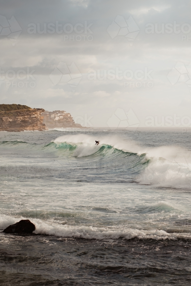 A man on his surfing board is riding a huge wave - Australian Stock Image