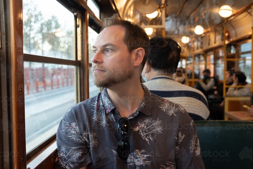 A man sitting in a famous historic Melbourne W Class tram looking out the window - Australian Stock Image