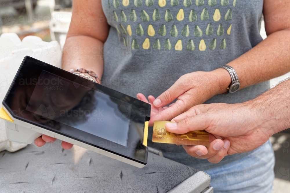 A man using technology making a mobile eftpos payment with a credit card - Australian Stock Image