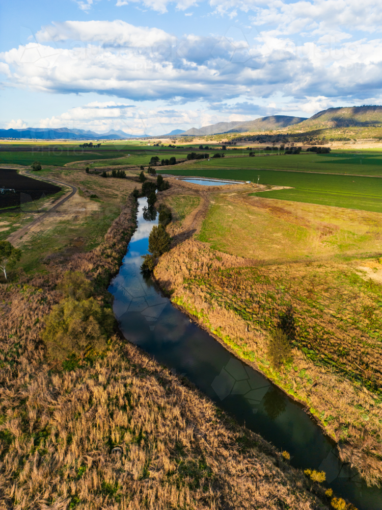 A meandering creek  with water surrounded by agricultural fields - Australian Stock Image