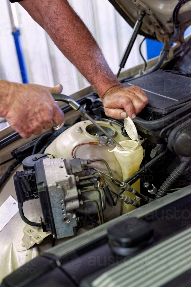 A mechanic servicing a luxury car in his workshop on the Gold Coast - Australian Stock Image