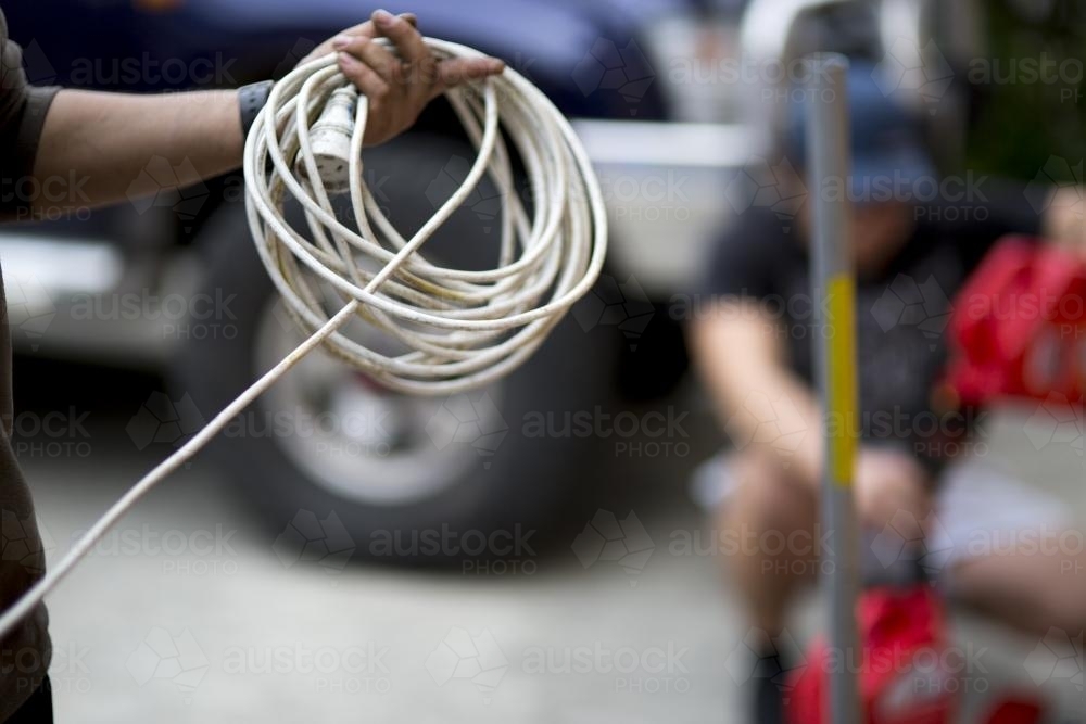 Image of A mechanic winding an extension cord. Austockphoto