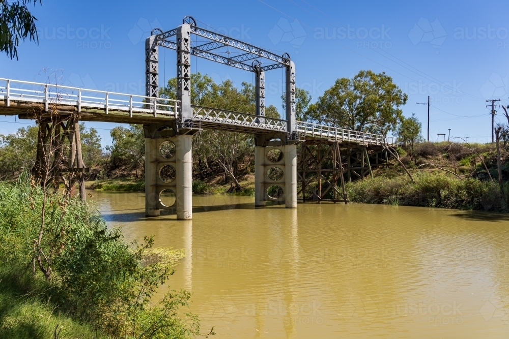 A murky river flowing under a deserted lift span bridge - Australian Stock Image