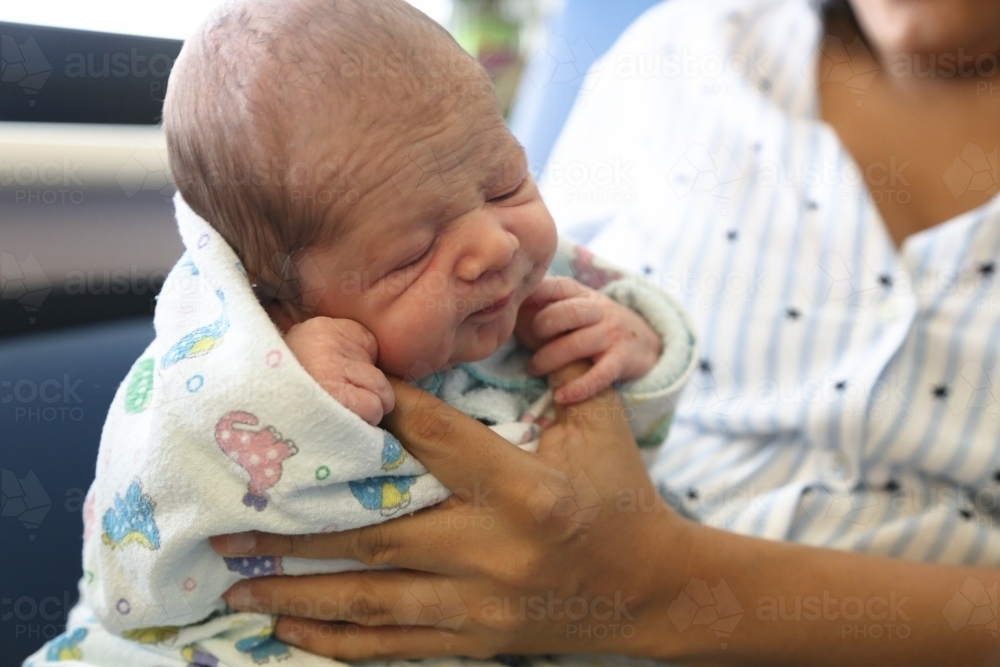 A newborn baby being held upright - Australian Stock Image