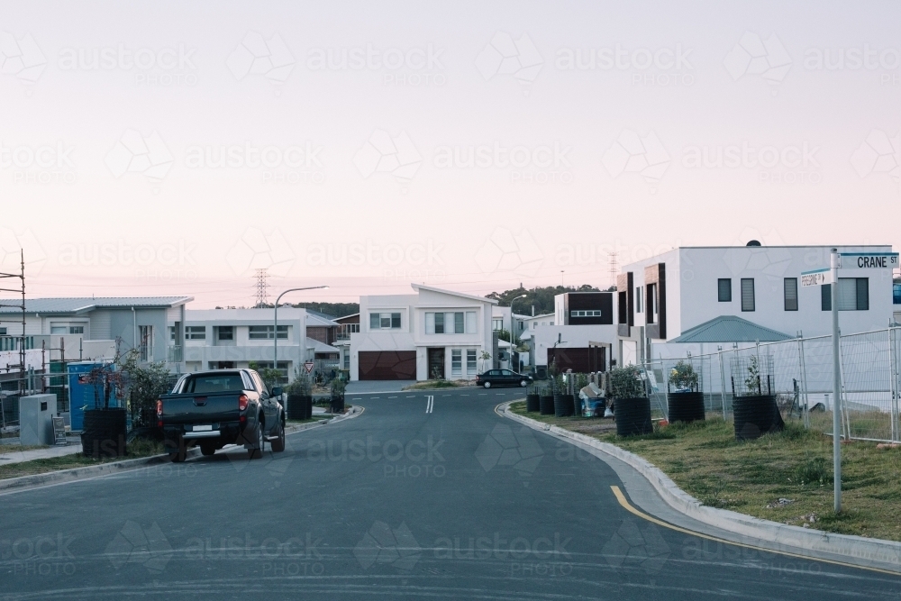 A newly developed suburban street with modern homes, parked cars on street at dusk - Australian Stock Image