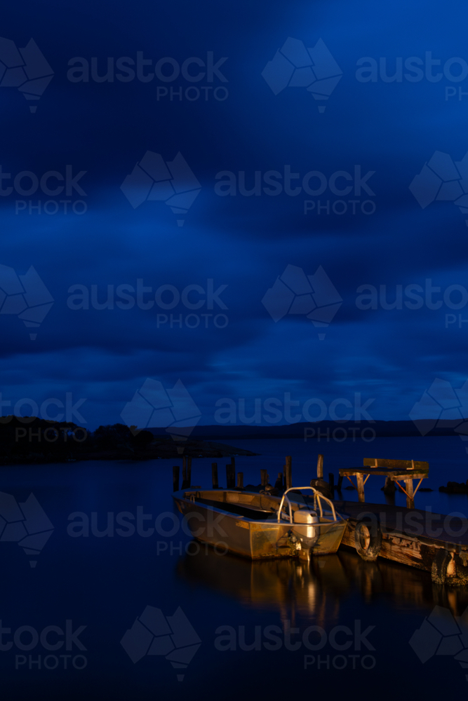 A night photo with light-painting of a recreational fishing boat at dock and rain clouds rolling in. - Australian Stock Image