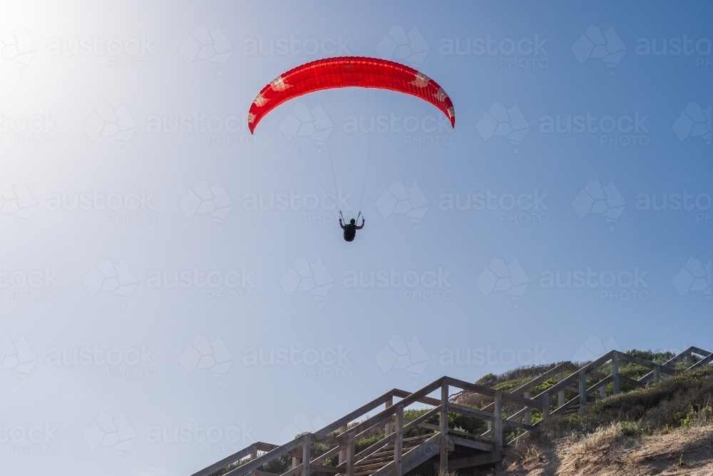 A parasailer silhouetted high above a staircase in a bright blue sky - Australian Stock Image