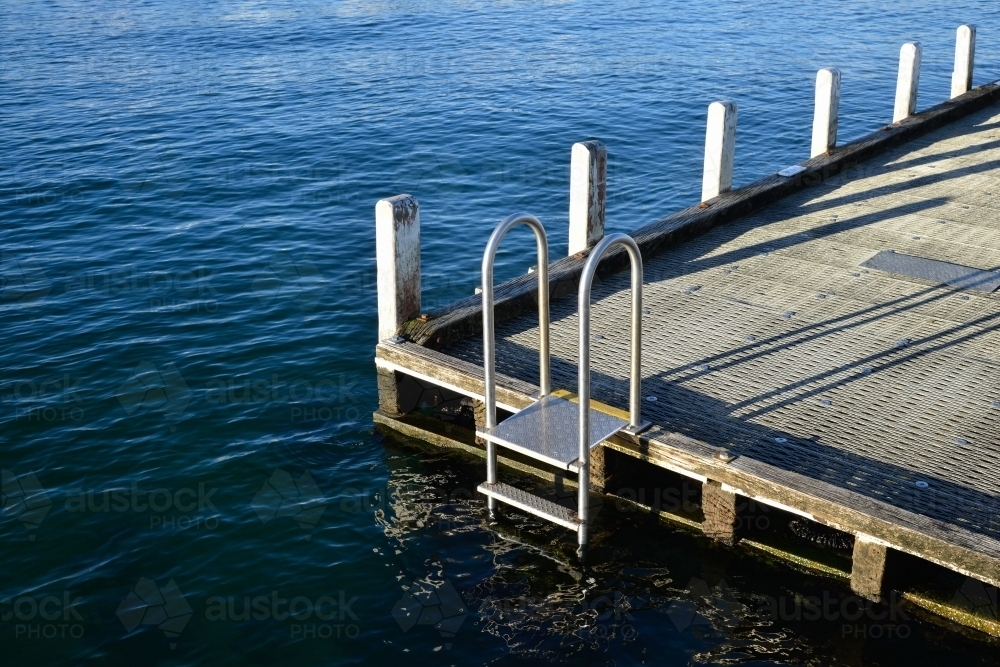 A pier with a ladder leading into the ocean for swimmers - Australian Stock Image