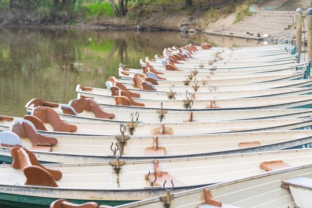 A row of identical row boats lined up at a dock - Australian Stock Image