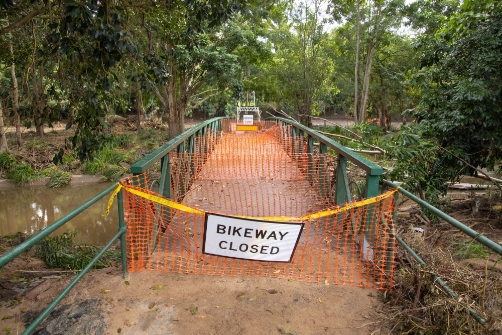 A safety barrier blocks a bridge crossing along a suburban bikeway after a flood event - Australian Stock Image