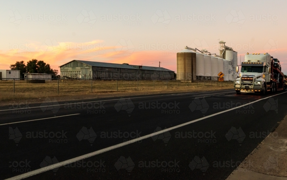 A semitrailer driving past grain silos with pretty sunset in the background - Australian Stock Image