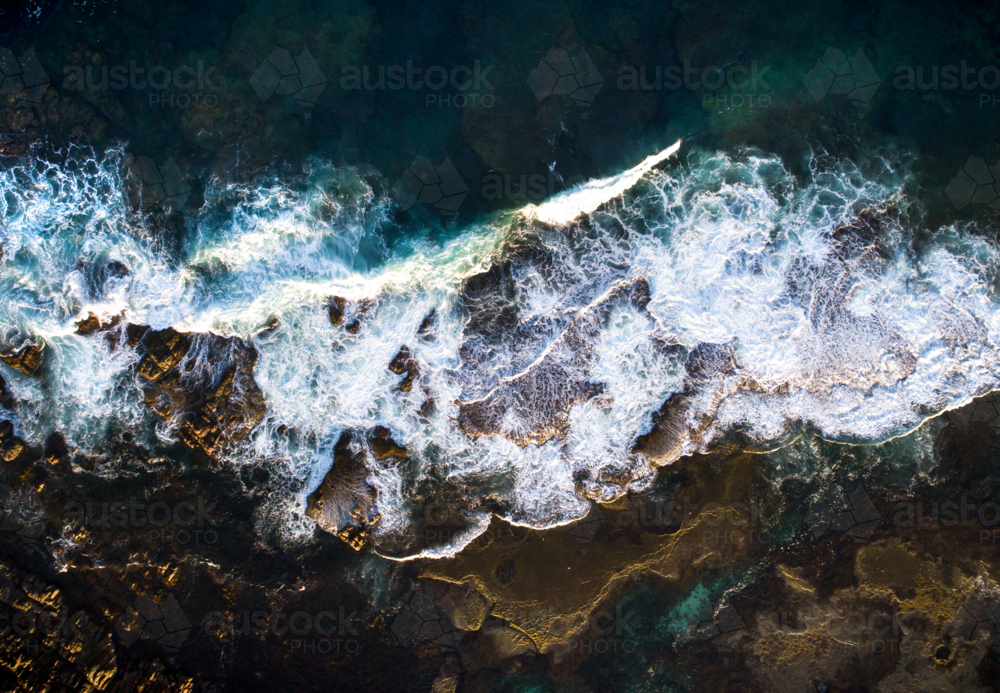 A series of waves break over an exposed reef - Australian Stock Image