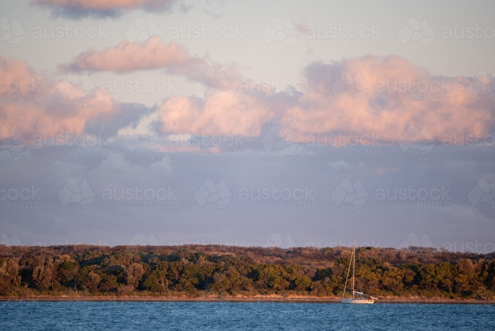 A single yacht moored off Jibbon point at sunset - Australian Stock Image