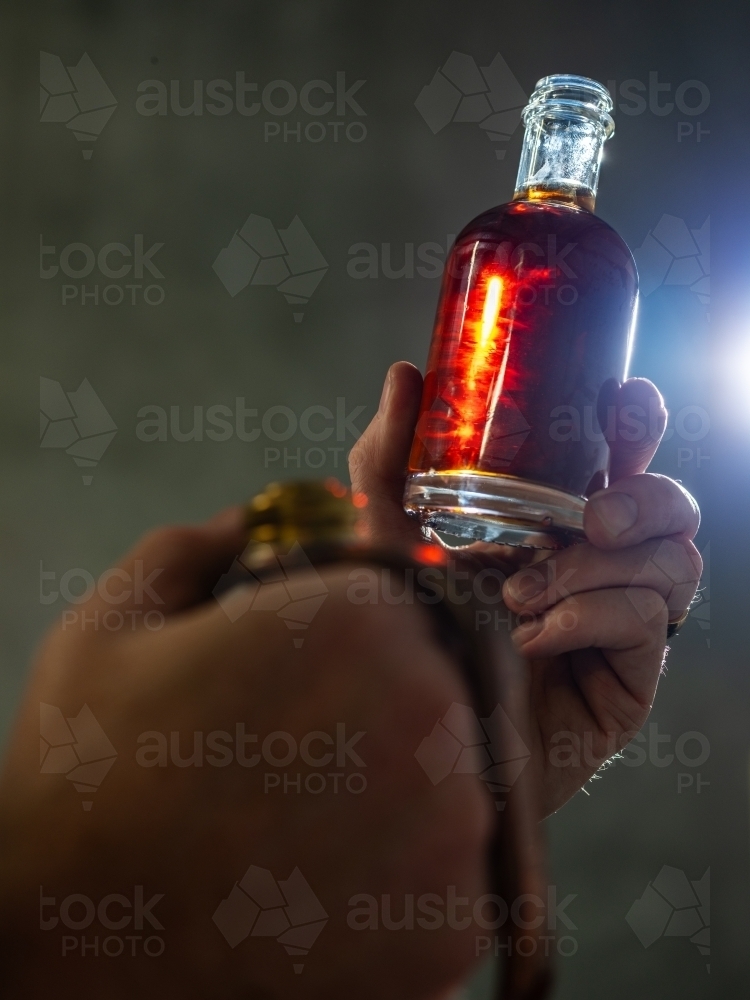 A small bottle of whisky held against a light source - Australian Stock Image