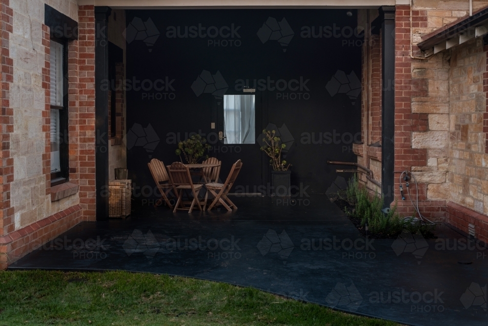 a small courtyard patio, painted black, with timber furniture and plants - Australian Stock Image